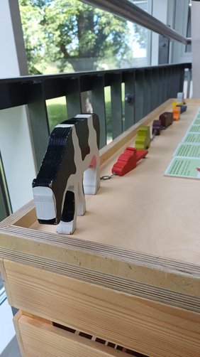 Spielerische Station mit Holzfiguren zur Lebensmittelproduktion und Lieferkette